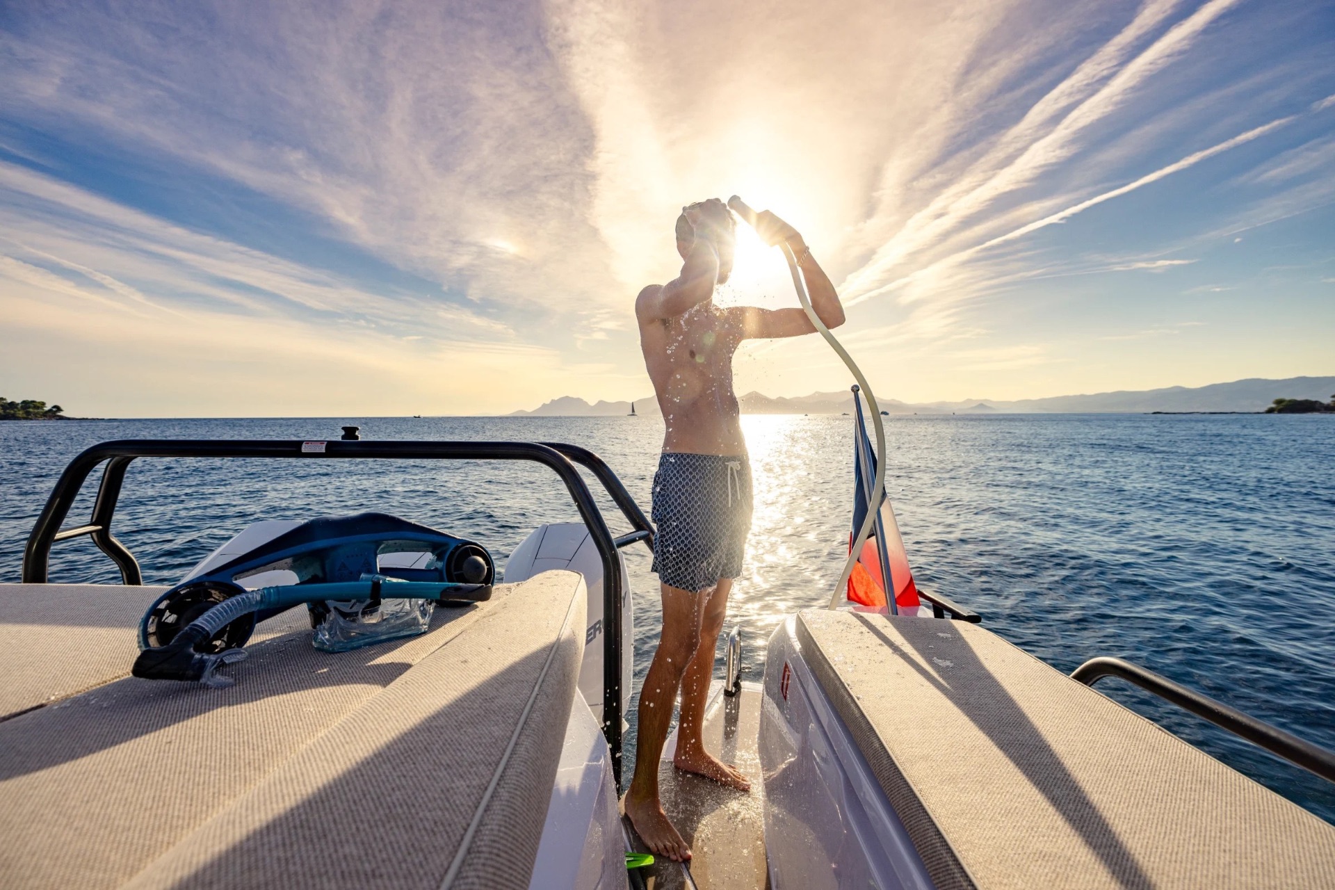 Guest using the deck shower on the swim platform at sunset